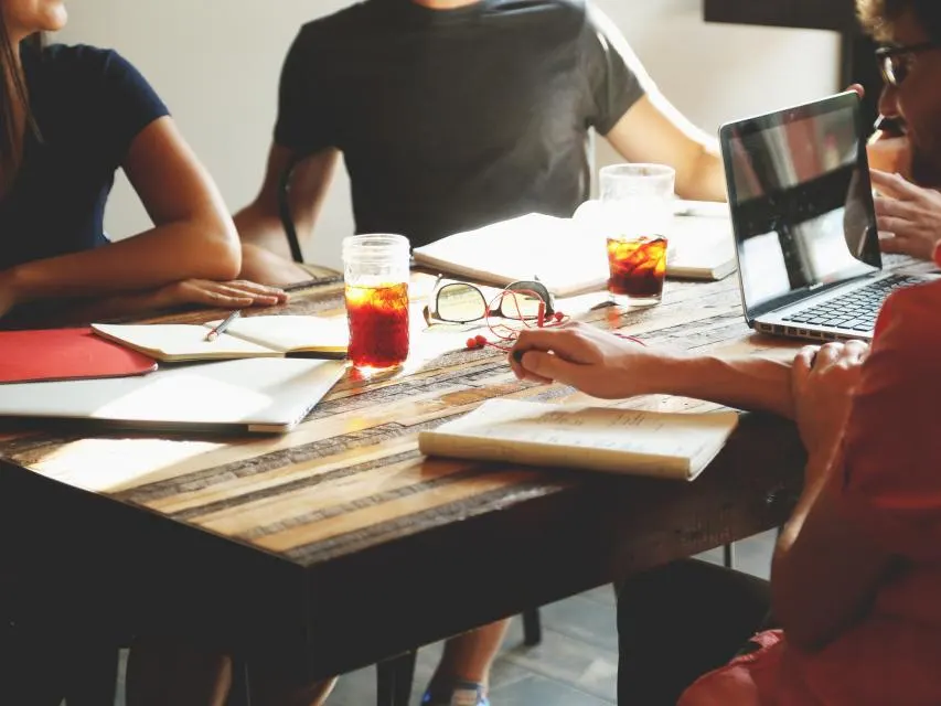 People meeting around a table with laptops and papers